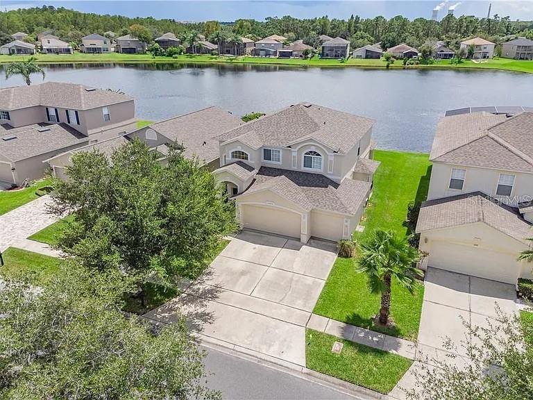 An aerial view shows suburban houses with driveways situated along a lake — 14802 YORKSHIRE RUN DRIVE, ORLANDO, FL