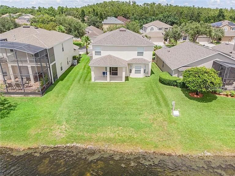 An aerial view shows a two-story house with a backyard lawn bordering a pond — 14802 YORKSHIRE RUN DRIVE, ORLANDO, FL