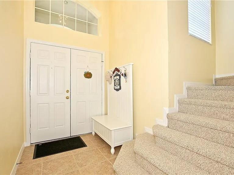 An entryway features a white double door, a storage bench, and carpeted stairs — 14802 YORKSHIRE RUN DRIVE, ORLANDO, FL