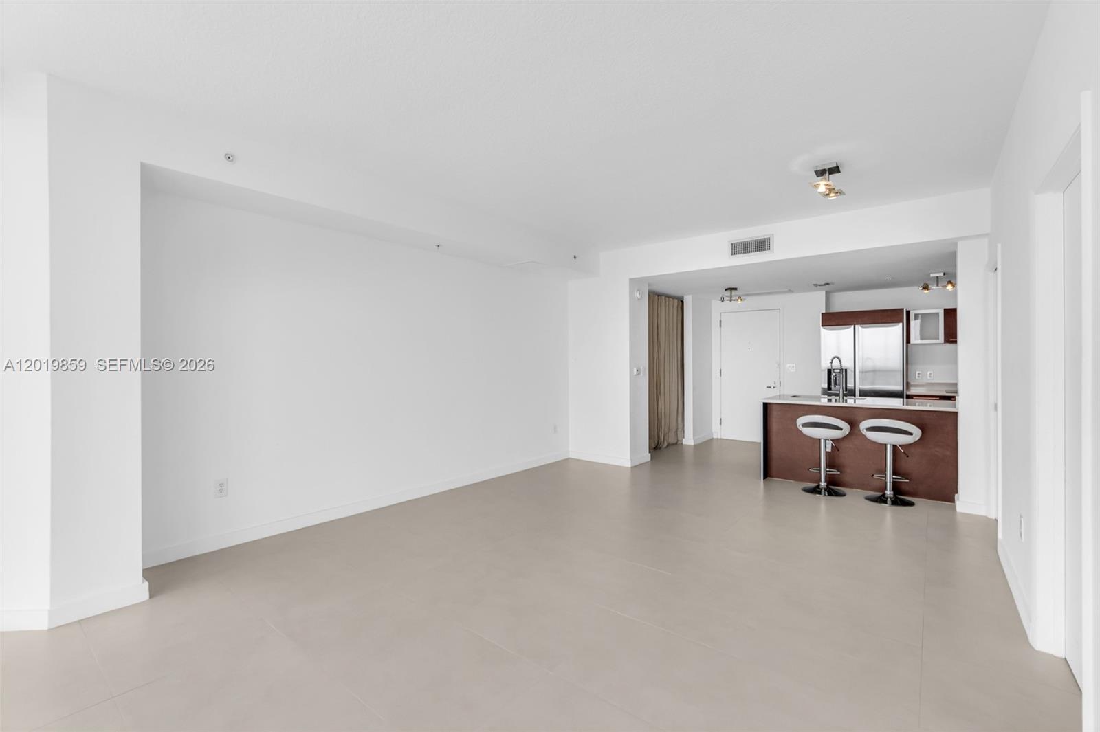 An open-concept living area features white walls, light tile flooring, and a kitchen breakfast bar — 1900 N Bayshore Dr # 3216, Miami FL 33132, MIAMI, FL