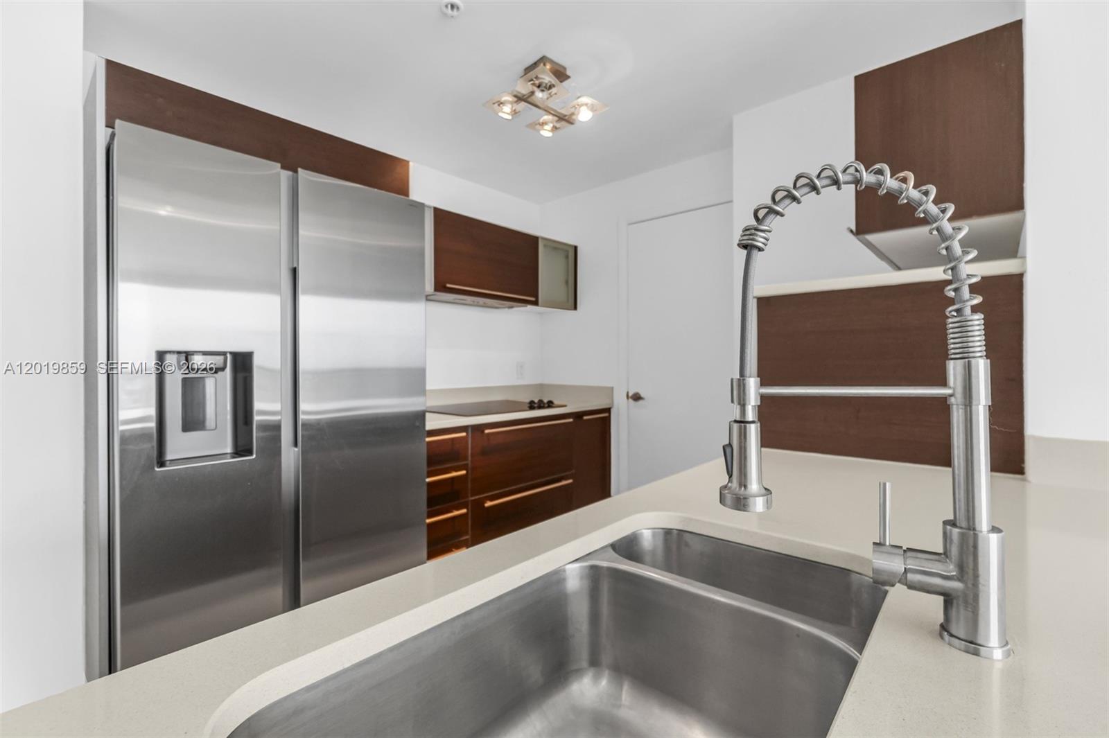A kitchen features stainless steel appliances, dark wood cabinetry, and a double-basin sink — 1900 N Bayshore Dr # 3216, Miami FL 33132, MIAMI, FL