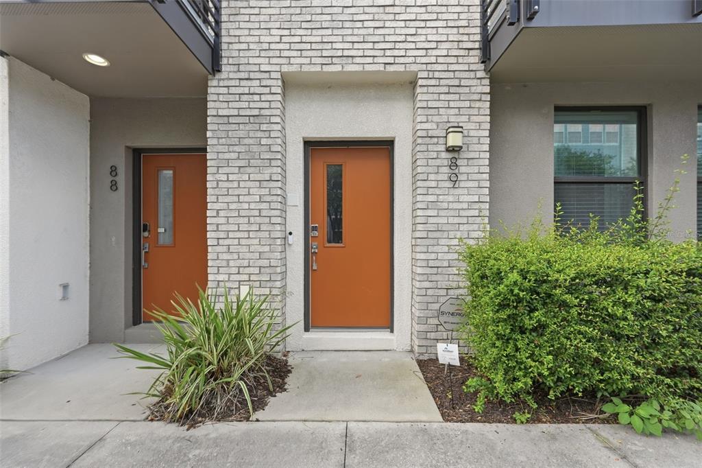 Two orange front doors with vertical windows are set into a light-colored brick exterior — 2511 N GRADY AVENUE UNIT 89, TAMPA, FL
