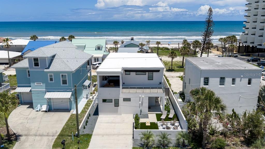 An aerial view shows three beach houses with a modern white home in the center — 1309 S ATLANTIC AVENUE, NEW SMYRNA BEACH, FL