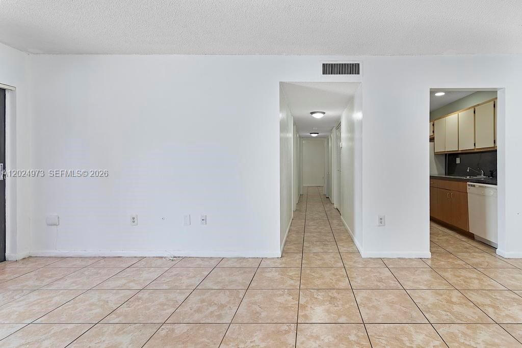 A view of a room with tiled floors, a hallway, and an adjacent kitchen — 7403 SW 152nd Ave # 2, Miami FL 33193, MIAMI, FL