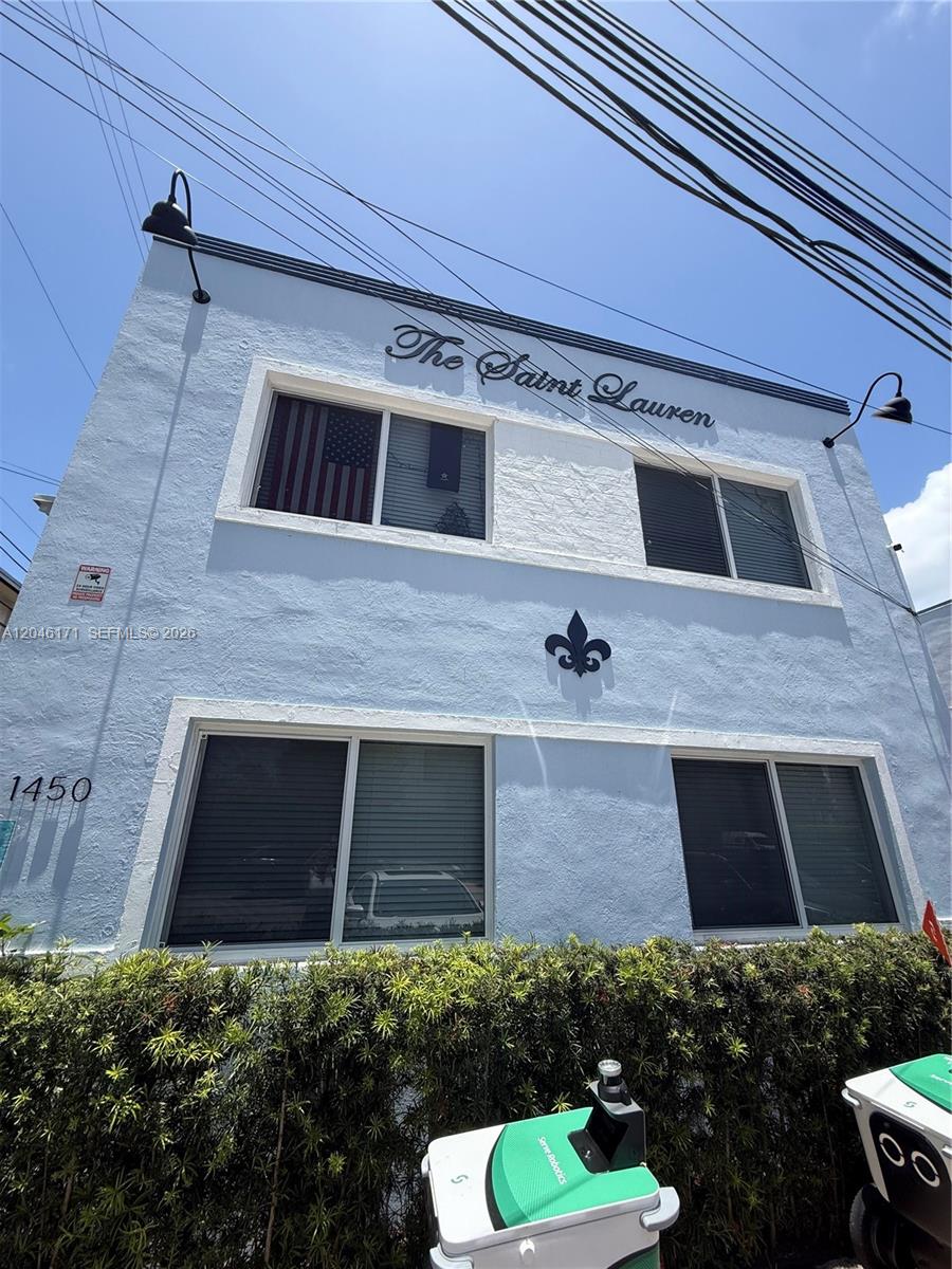 The exterior of a two-story light blue building features a sign reading The Saint Lauren — 1450 Lenox Ave # 5, Miami Beach FL 33139, MIAMI BEACH, FL