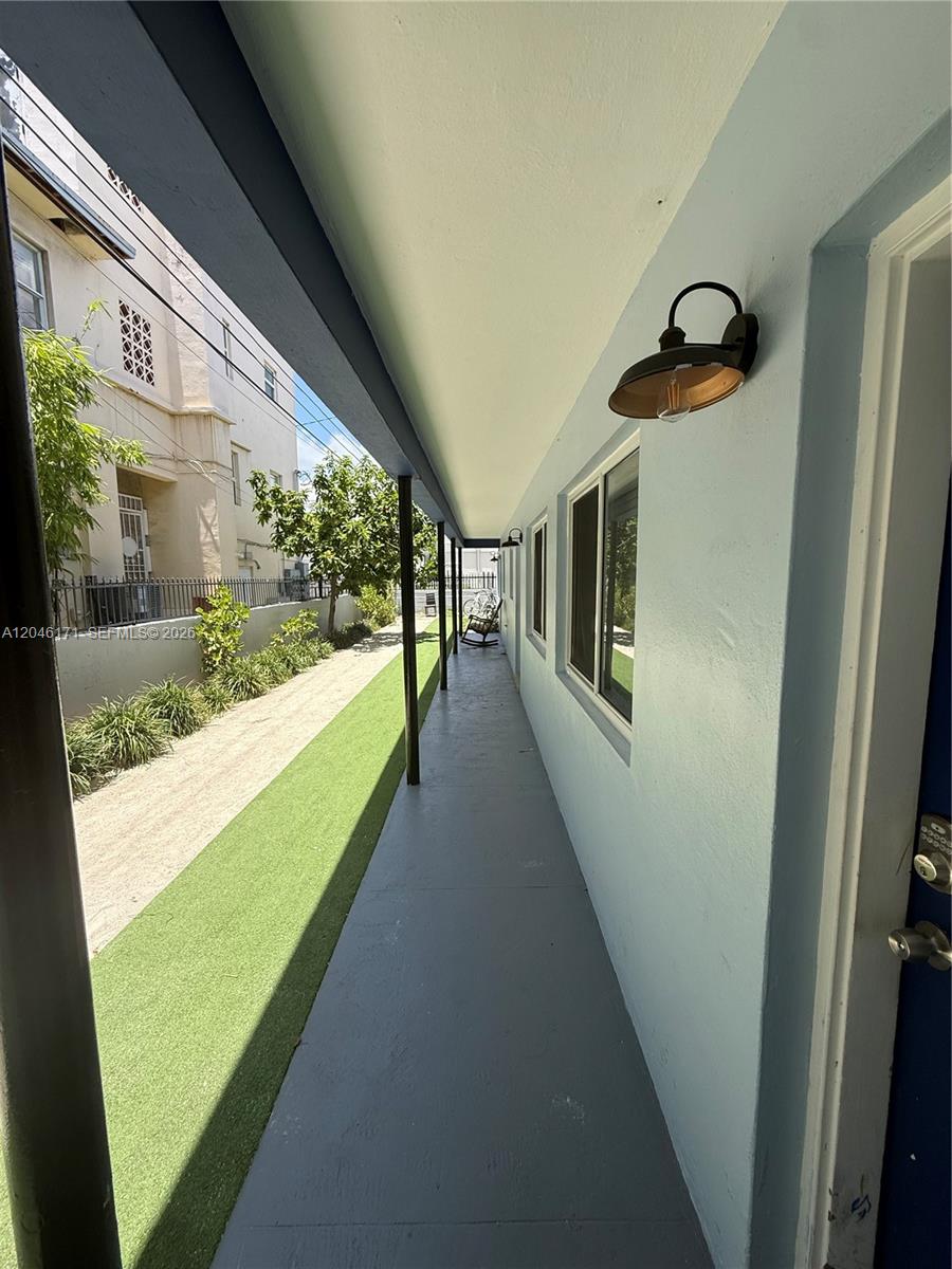 A covered outdoor walkway with a concrete floor runs alongside a light blue building — 1450 Lenox Ave # 5, Miami Beach FL 33139, MIAMI BEACH, FL