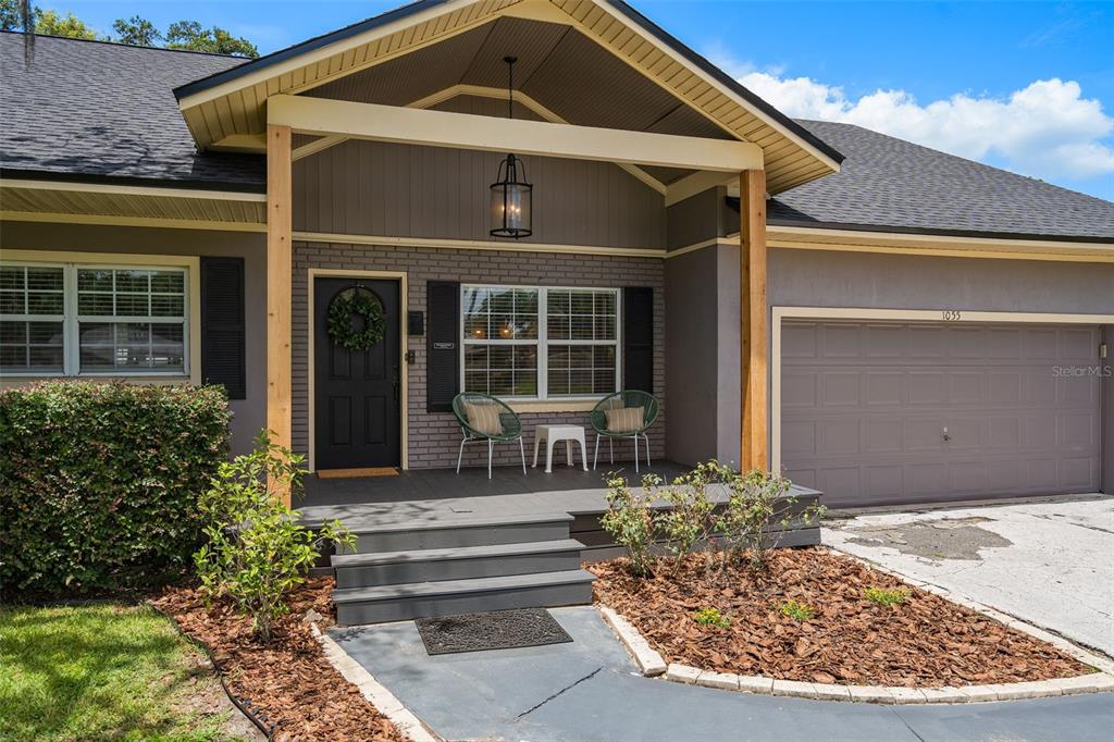 The exterior of a house features a covered porch, a front door, and a garage — 1055 DRUID DRIVE, MAITLAND, FL