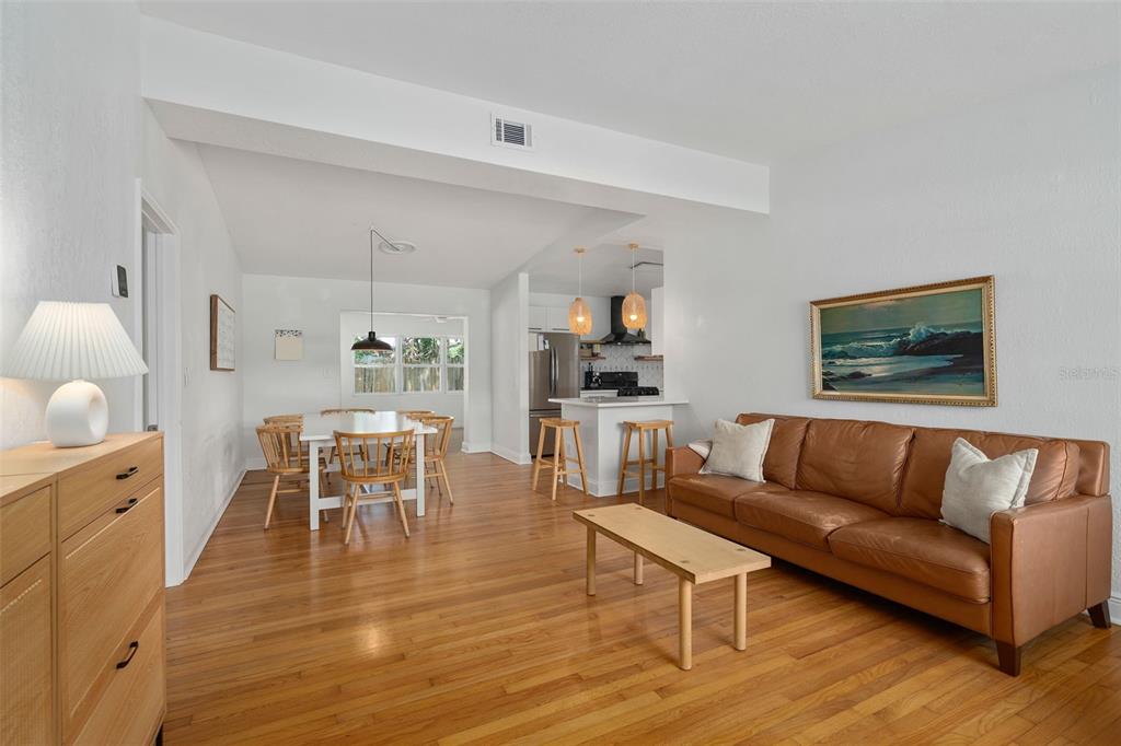 An open-concept living and dining area features hardwood floors, a leather sofa, and a kitchen — 1055 DRUID DRIVE, MAITLAND, FL