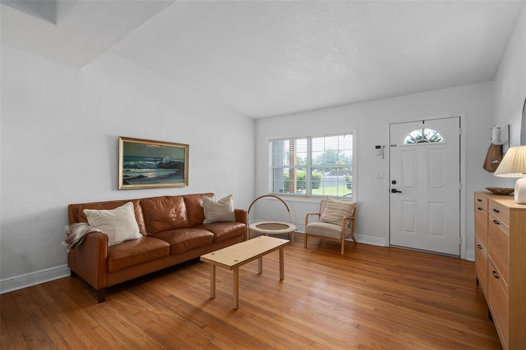 A living room features a brown leather sofa, wood flooring, a coffee table, and front door — 1055 DRUID DRIVE, MAITLAND, FL