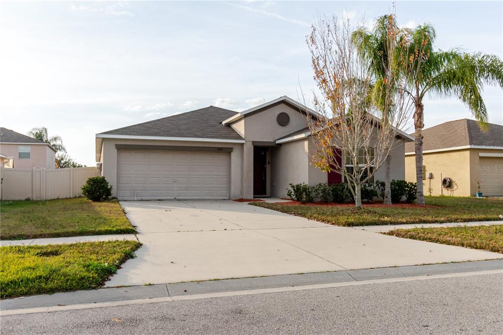 A single-story suburban house with a two-car garage, concrete driveway, and a palm tree — 304 CASCADE BEND, RUSKIN, FL