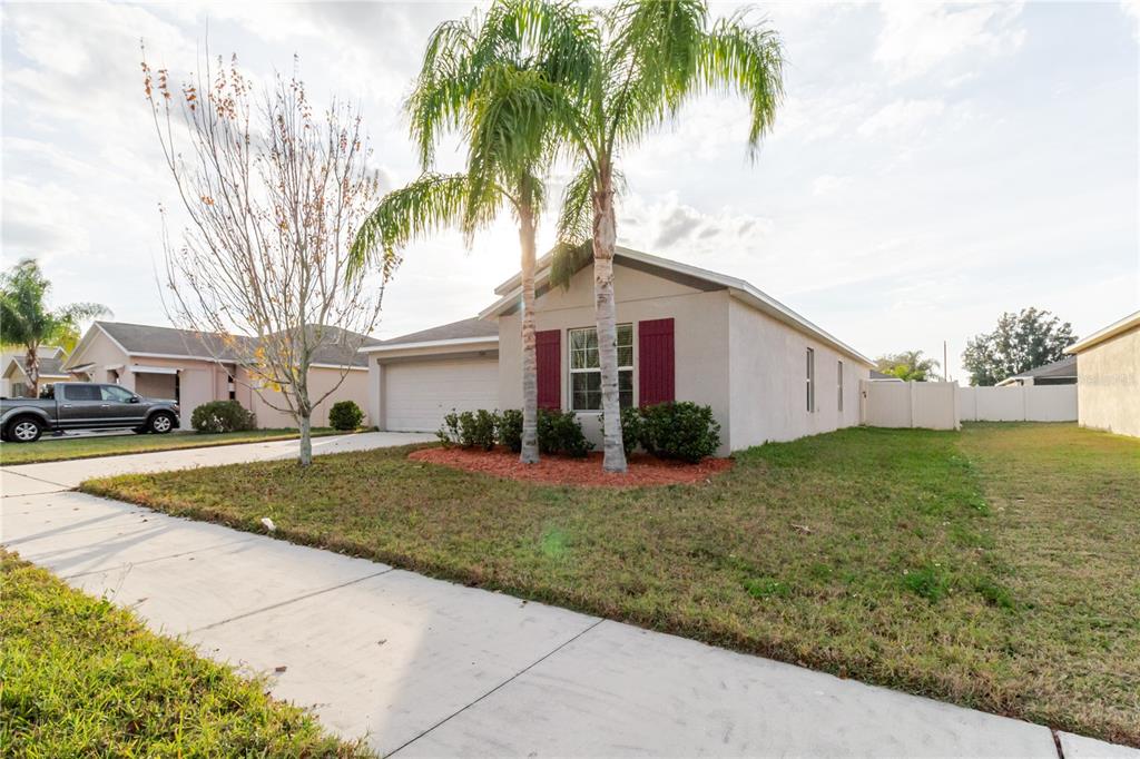 A single-story house with a beige stucco exterior, red shutters, and two palm trees — 304 CASCADE BEND, RUSKIN, FL