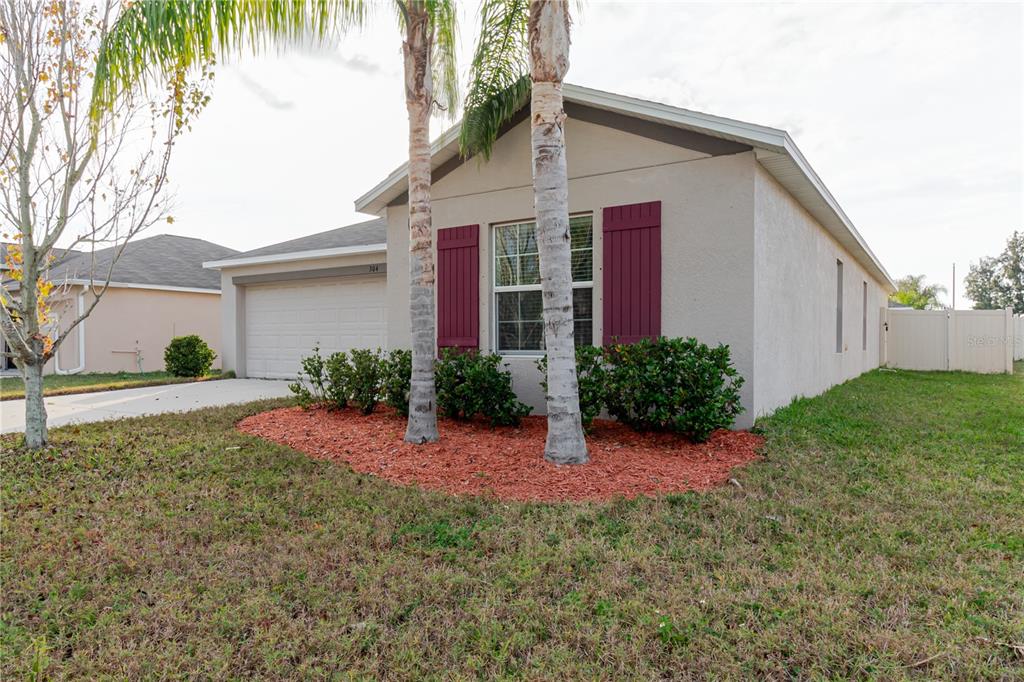 A single-story house with a two-car garage, red shutters, and two palm trees in front — 304 CASCADE BEND, RUSKIN, FL