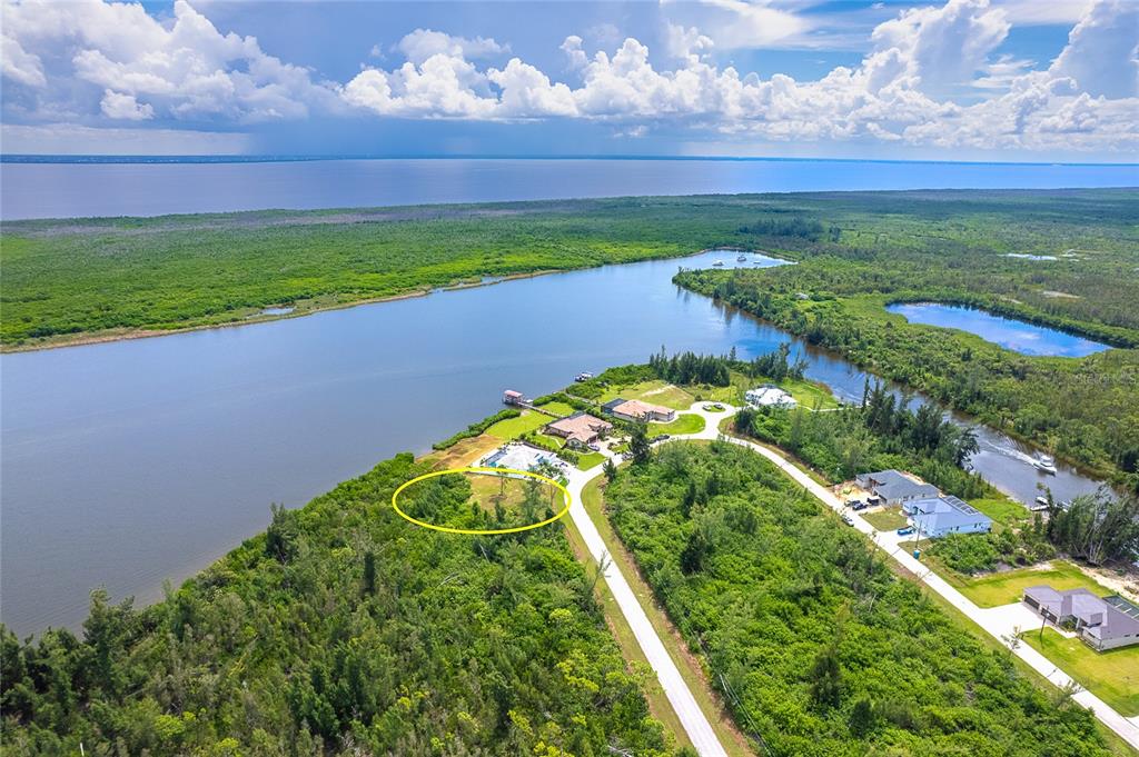 An aerial view shows a waterfront property with a cleared lot circled in yellow — 16468 LIGGETT CIRCLE, PORT CHARLOTTE, FL