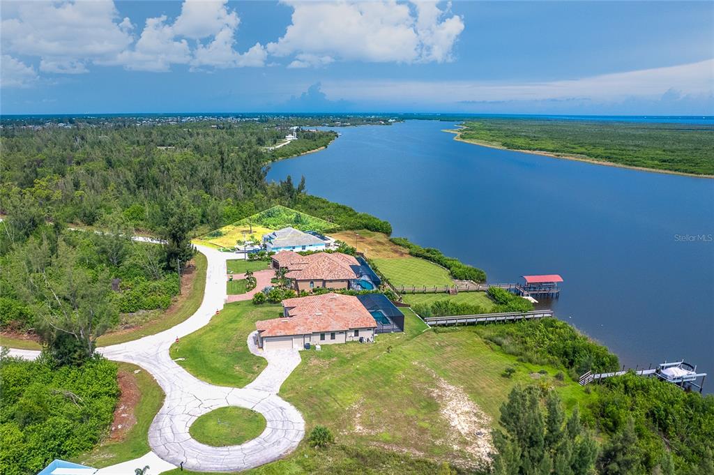 An aerial view of a waterfront property featuring two houses, a driveway, and a dock — 16468 LIGGETT CIRCLE, PORT CHARLOTTE, FL