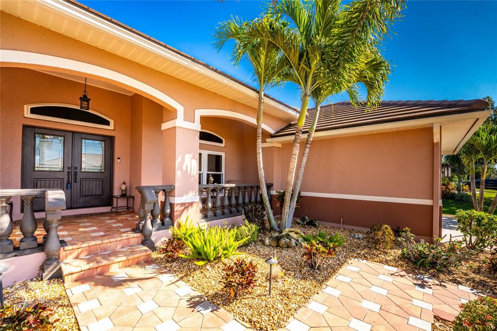 A peach-colored house exterior features a tiled entryway, double front doors, and palm trees — 310 CORAL CREEK DRIVE, PLACIDA, FL
