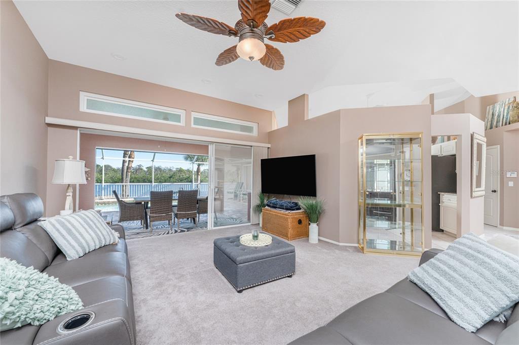 A living room with gray sofas, a central ottoman, and a view of a pool — 310 CORAL CREEK DRIVE, PLACIDA, FL