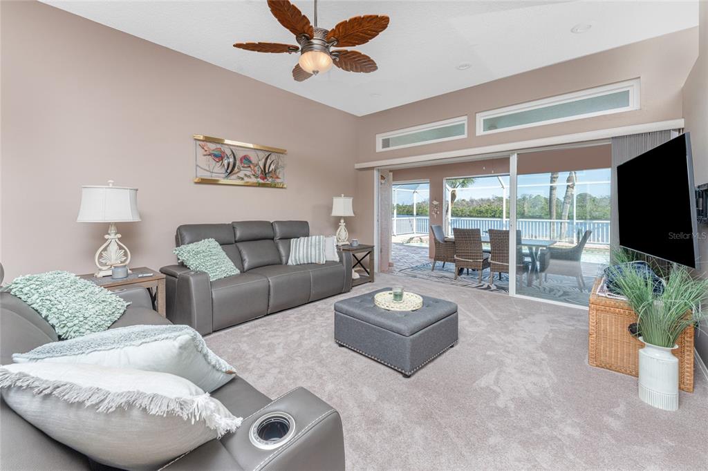 A living room features gray leather sofas, a matching ottoman, and sliding doors to a patio — 310 CORAL CREEK DRIVE, PLACIDA, FL