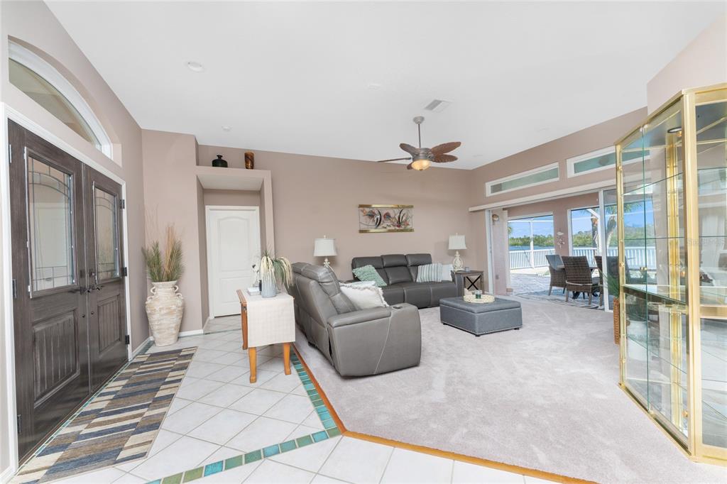 A living room with gray furniture, carpet, tile flooring, and a glass display cabinet — 310 CORAL CREEK DRIVE, PLACIDA, FL