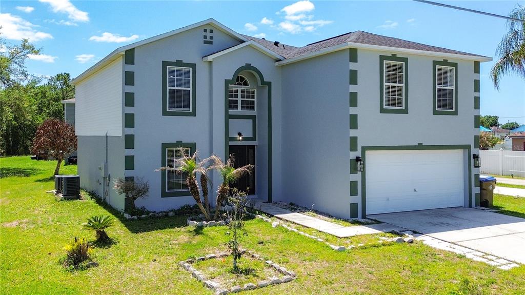 A two-story house with light gray stucco walls, dark green trim, and a two-car garage — 965 ALSACE DRIVE, KISSIMMEE, FL