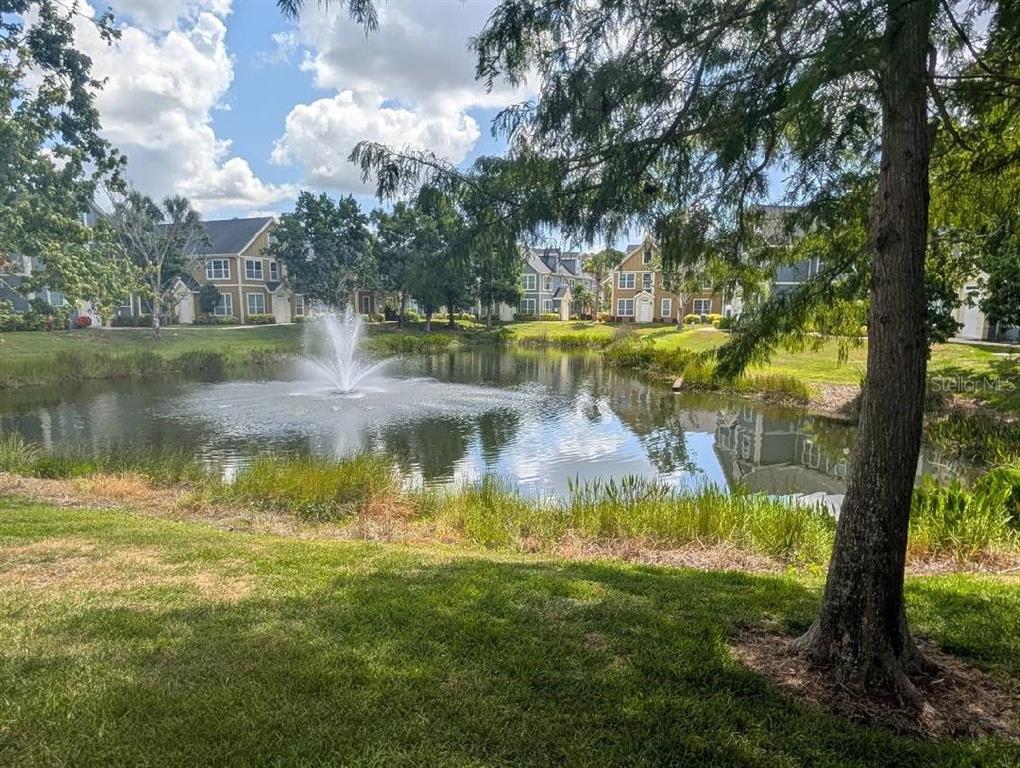 A fountain sprays water in the center of a pond surrounded by residential buildings — 5611 BIDWELL PARKWAY UNIT 204, SARASOTA, FL