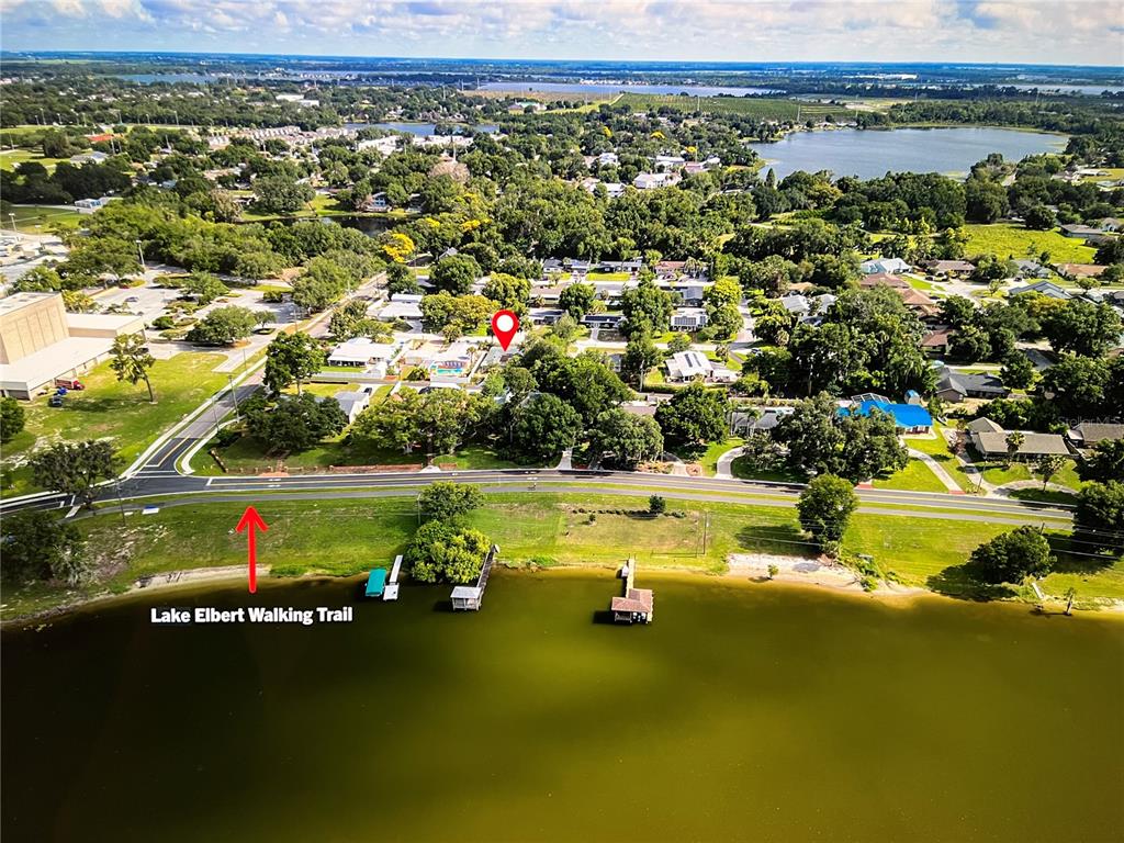 An aerial view shows a residential neighborhood bordering a lake with a walking trail — 6 GOLFVIEW CIRCLE NE, WINTER HAVEN, FL