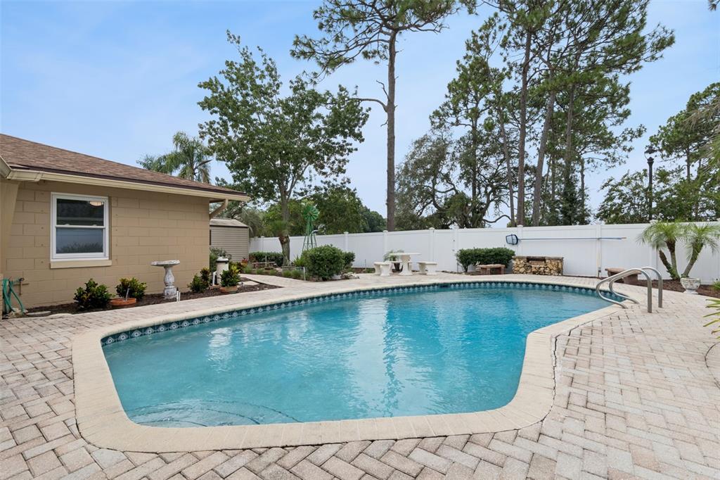 A backyard features a kidney-shaped swimming pool surrounded by a brick paver patio and fence — 1391 AVALON BOULEVARD, CASSELBERRY, FL
