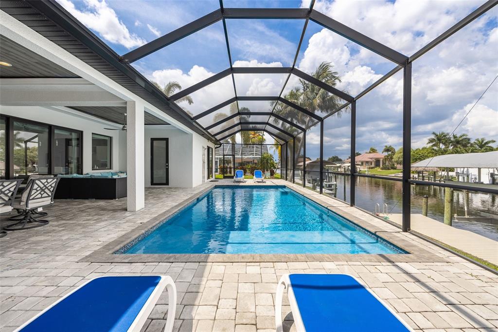 A swimming pool with a screened enclosure sits on a patio overlooking a canal — 3619 SE 16TH PLACE, CAPE CORAL, FL