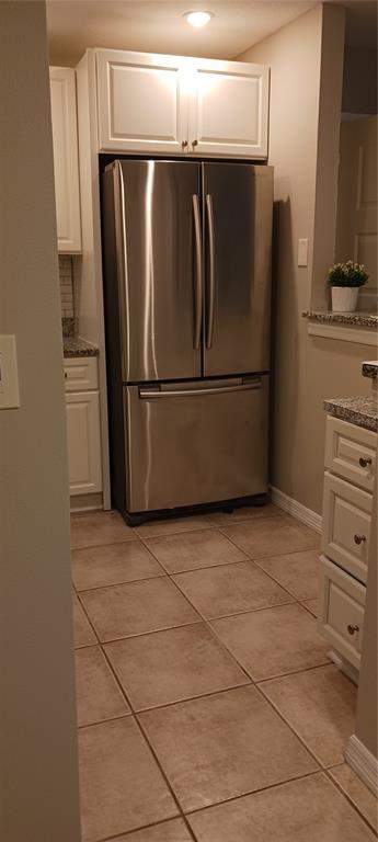 A stainless steel refrigerator is set between white cabinets and tile flooring in a kitchen — 3295 FOX CHASE UNIT 105, PALM HARBOR, FL