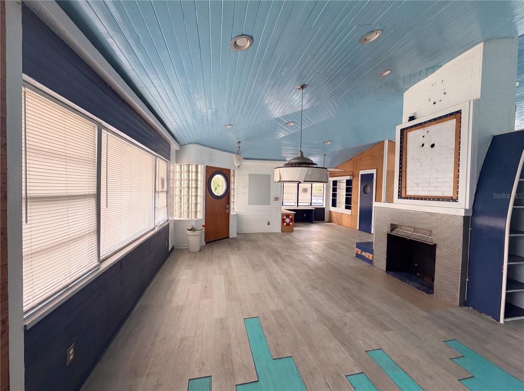 A living room features light wood flooring, a blue paneled ceiling, and a brick fireplace — 370 HARTFORD AVENUE, DAYTONA BEACH, FL