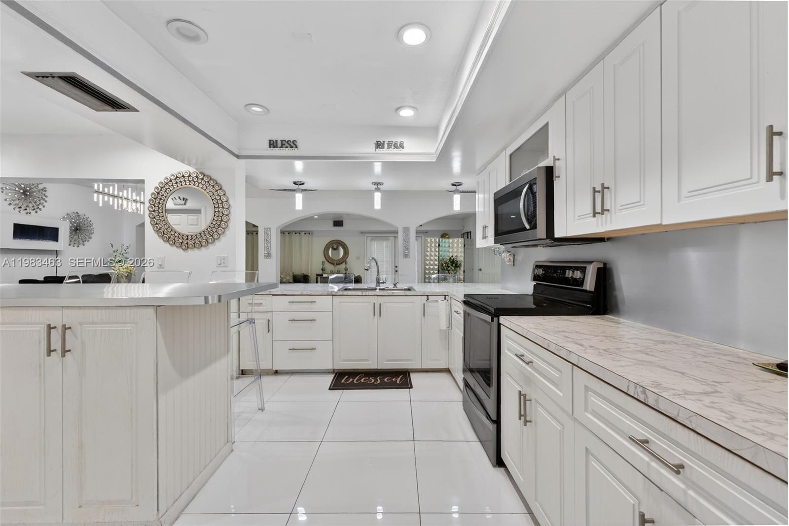 A white kitchen features marble-patterned countertops, stainless steel appliances, and a central island — 7777 Fairway Blvd, Miramar FL 33023, MIRAMAR, FL