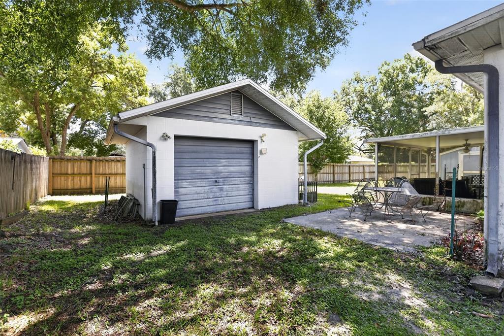A detached white garage with a gray door sits in a grassy backyard — 2651 SAMPLE STREET, KISSIMMEE, FL
