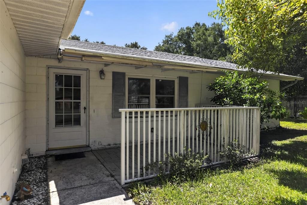 A white house exterior features a small patio enclosed by a white picket fence — 2651 SAMPLE STREET, KISSIMMEE, FL