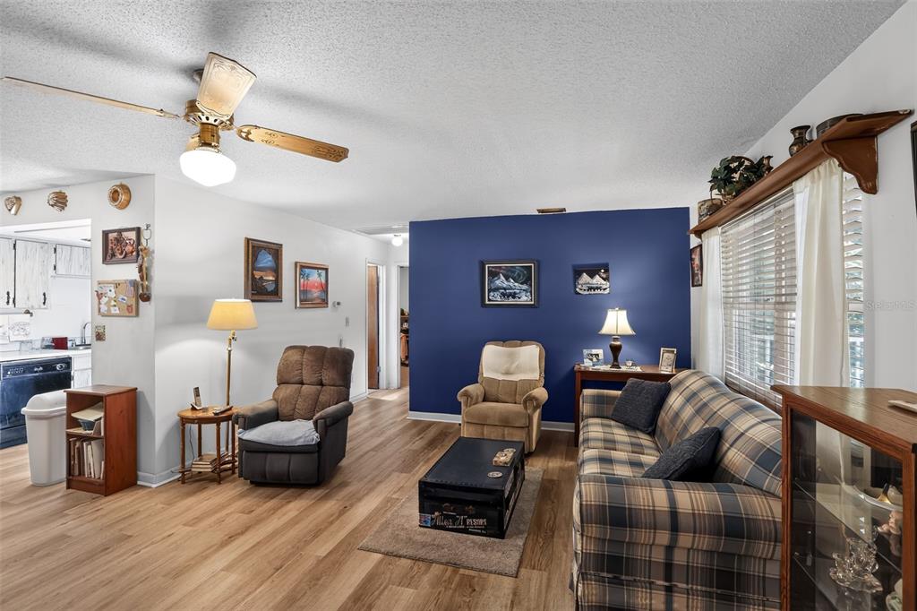 A living room features wood-look flooring, a blue accent wall, and a plaid sofa — 2651 SAMPLE STREET, KISSIMMEE, FL