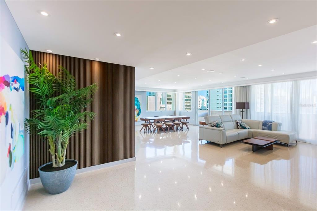 A spacious living and dining area features polished floors, recessed lighting, and a slatted wall — 1319 ASHFORD UNIT PH, SAN JUAN, PR