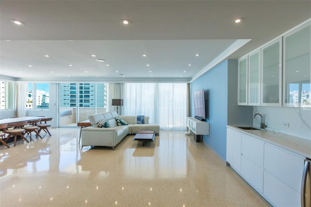 A bright, open-concept living and dining area features white tile floors and a kitchenette — 1319 ASHFORD UNIT PH, SAN JUAN, PR
