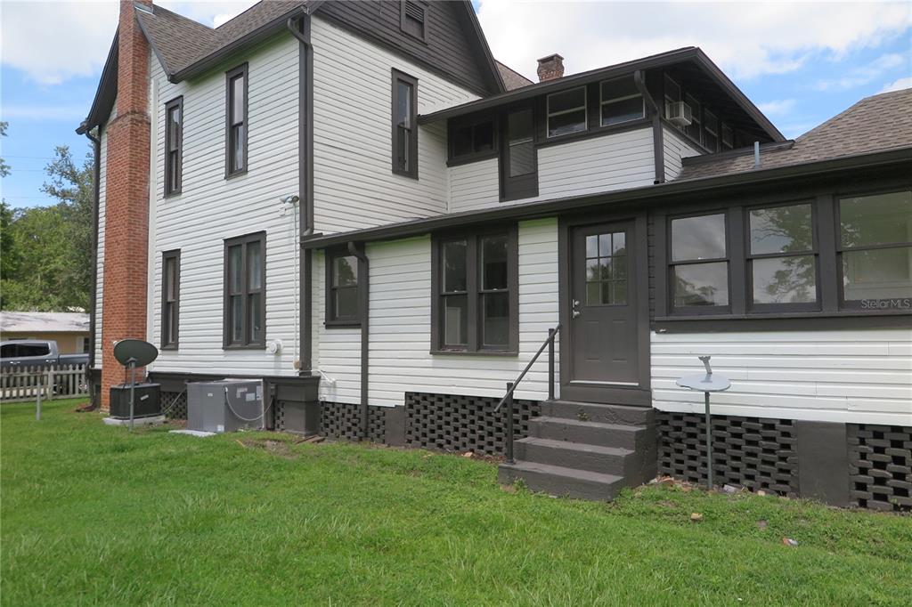 The exterior of a two-story house with white siding, dark trim, and a brick chimney — 105 SE 1ST AVENUE, LAKE BUTLER, FL