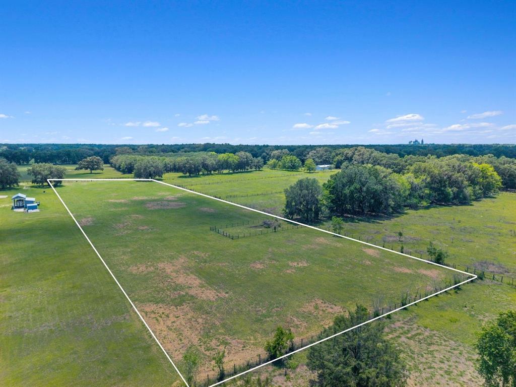 An aerial view shows a large, fenced, grassy plot of land under a clear sky — TBD NW 56TH LANE, NEWBERRY, FL