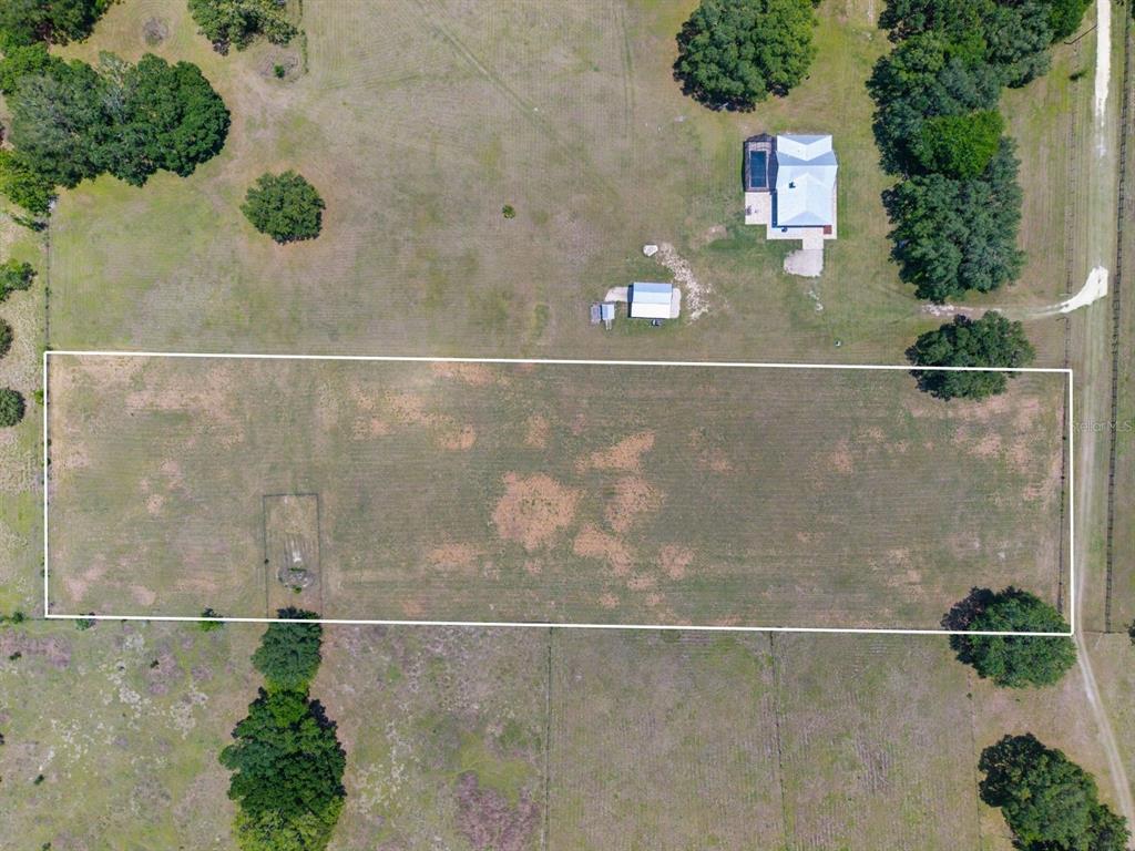 An aerial view shows a rectangular plot of land outlined in white near a house — TBD NW 56TH LANE, NEWBERRY, FL