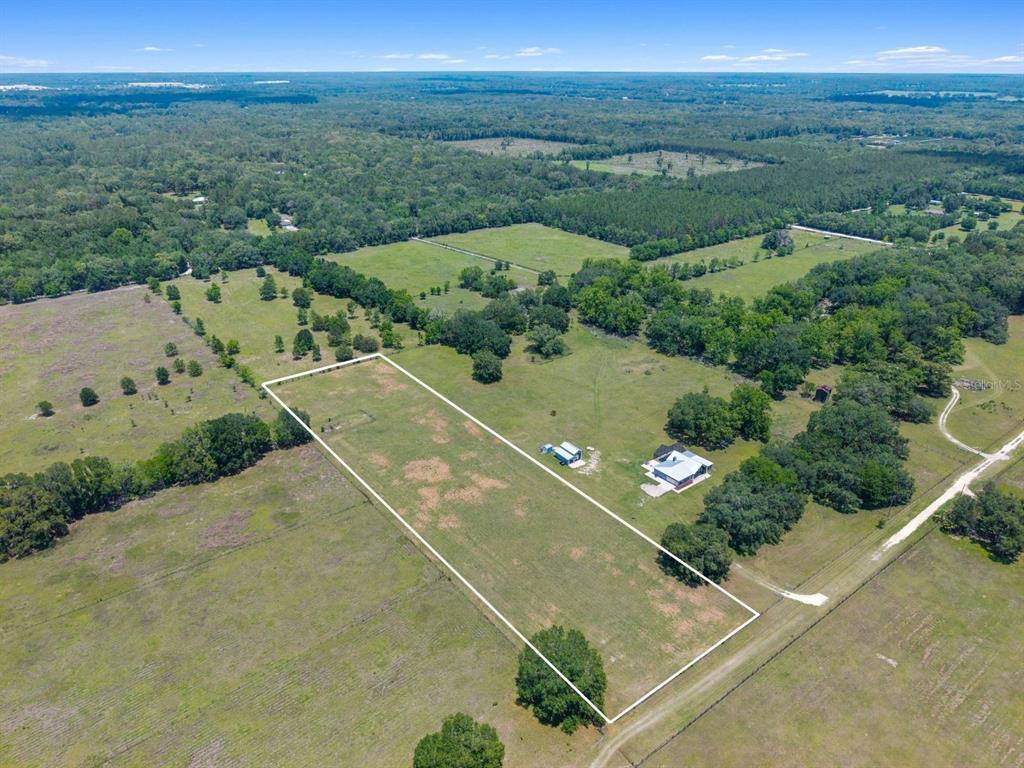 An aerial view shows a rectangular fenced pasture with a house and shed — TBD NW 56TH LANE, NEWBERRY, FL
