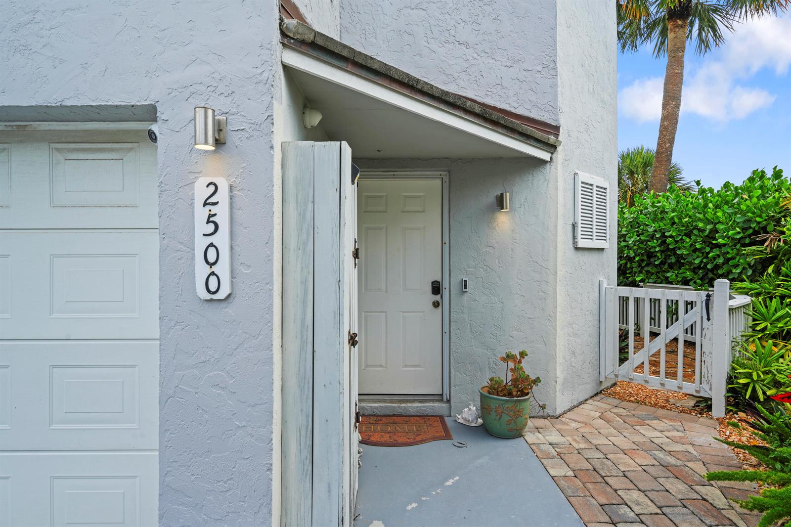 The exterior of a home features a white front door, a garage, and brick pavers — FORT PIERCE, FL