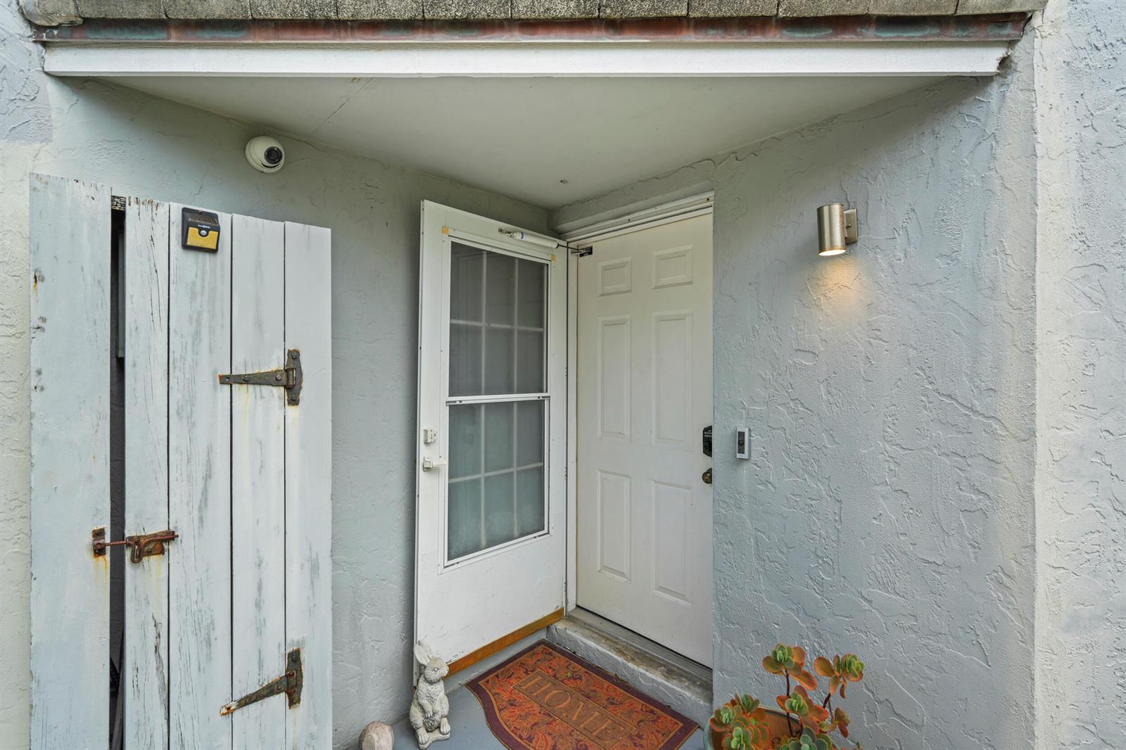 An exterior entryway features a white door, a screen door, and a weathered wooden gate — FORT PIERCE, FL