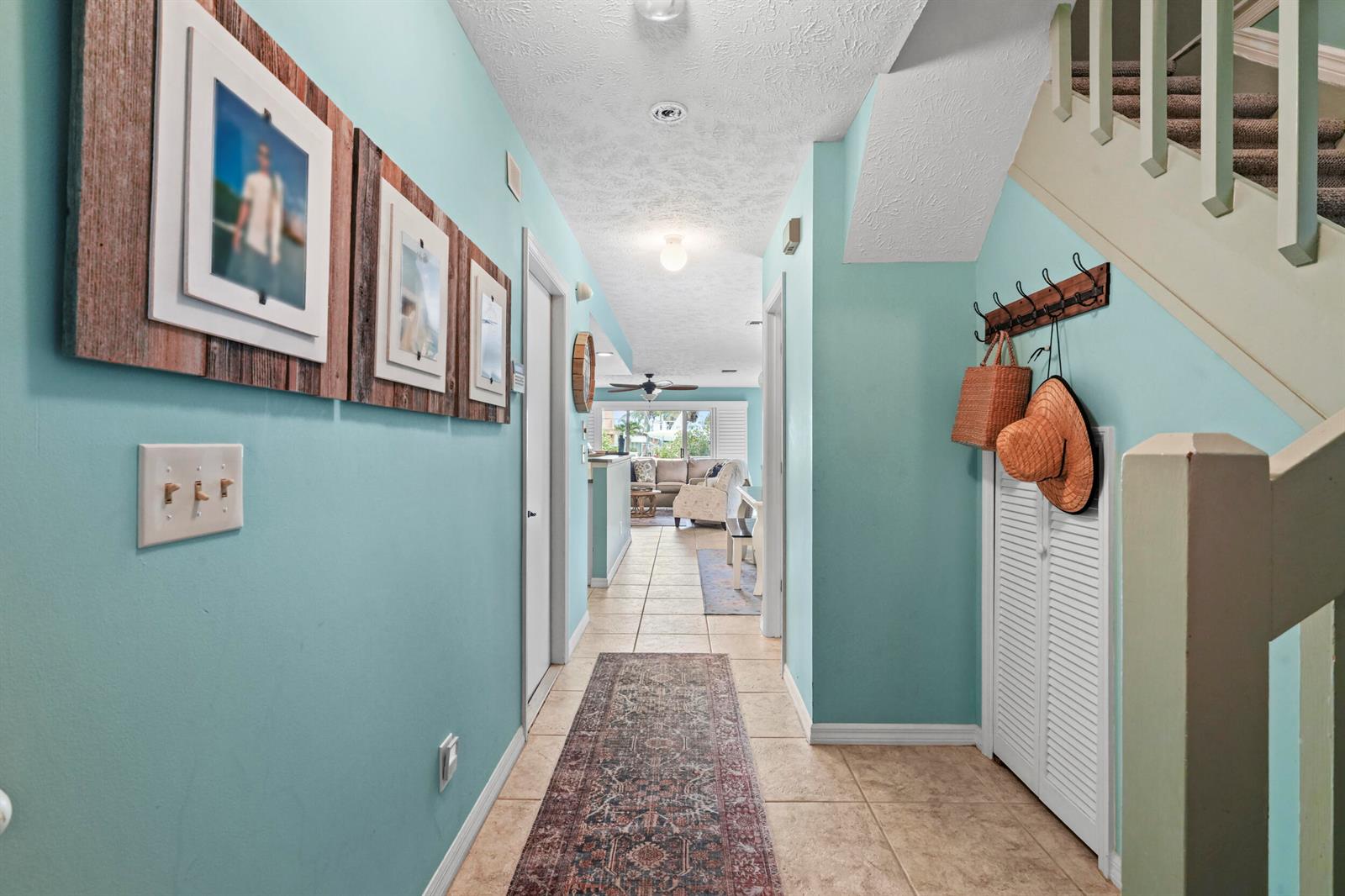 A hallway with light blue walls, tile flooring, a runner rug, and a staircase — FORT PIERCE, FL