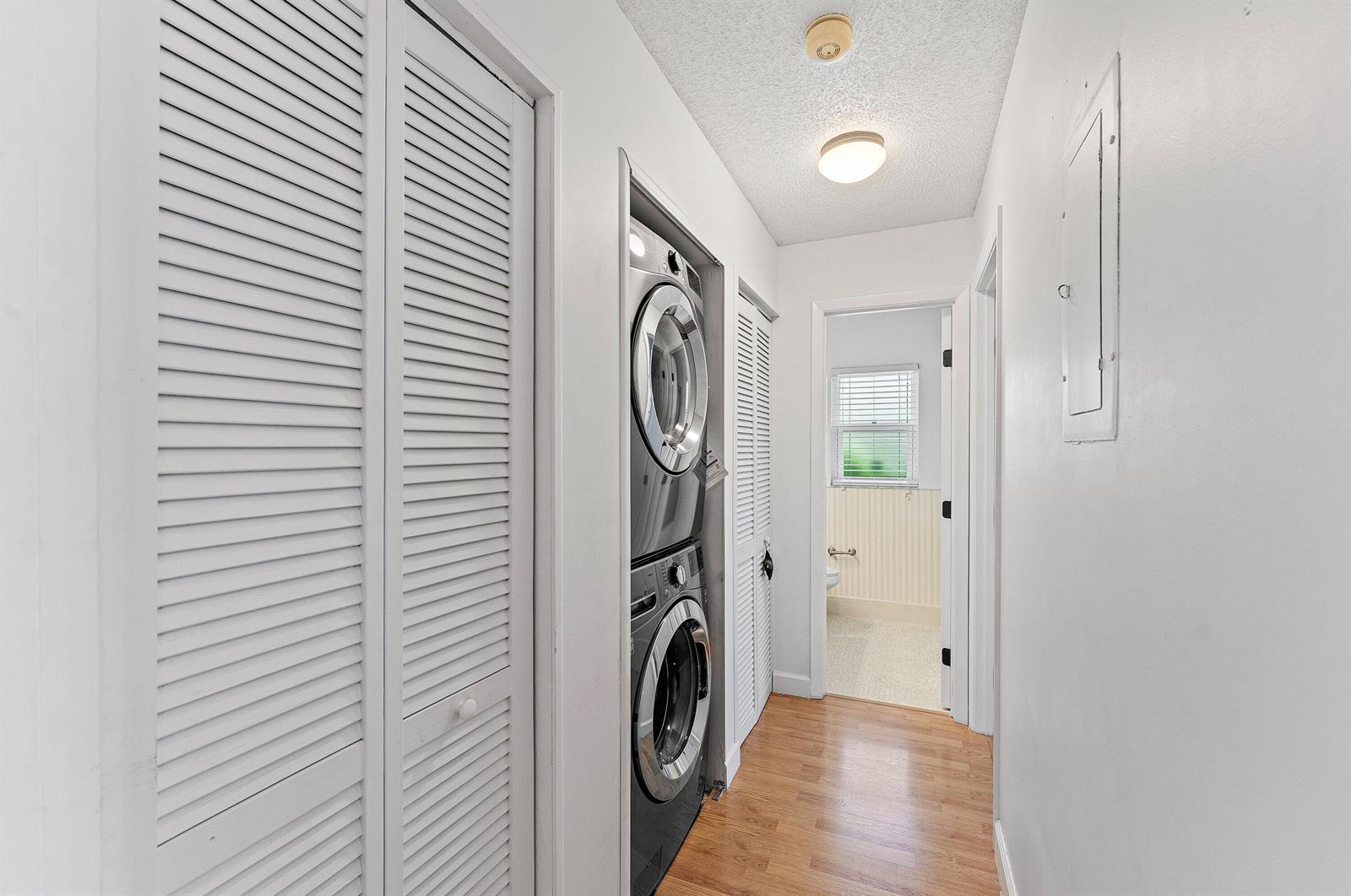 A laundry closet with a stacked washer and dryer sits in a hallway with flooring — 18855 Candlewick Drive, Boca Raton FL 33496, BOCA RATON, FL