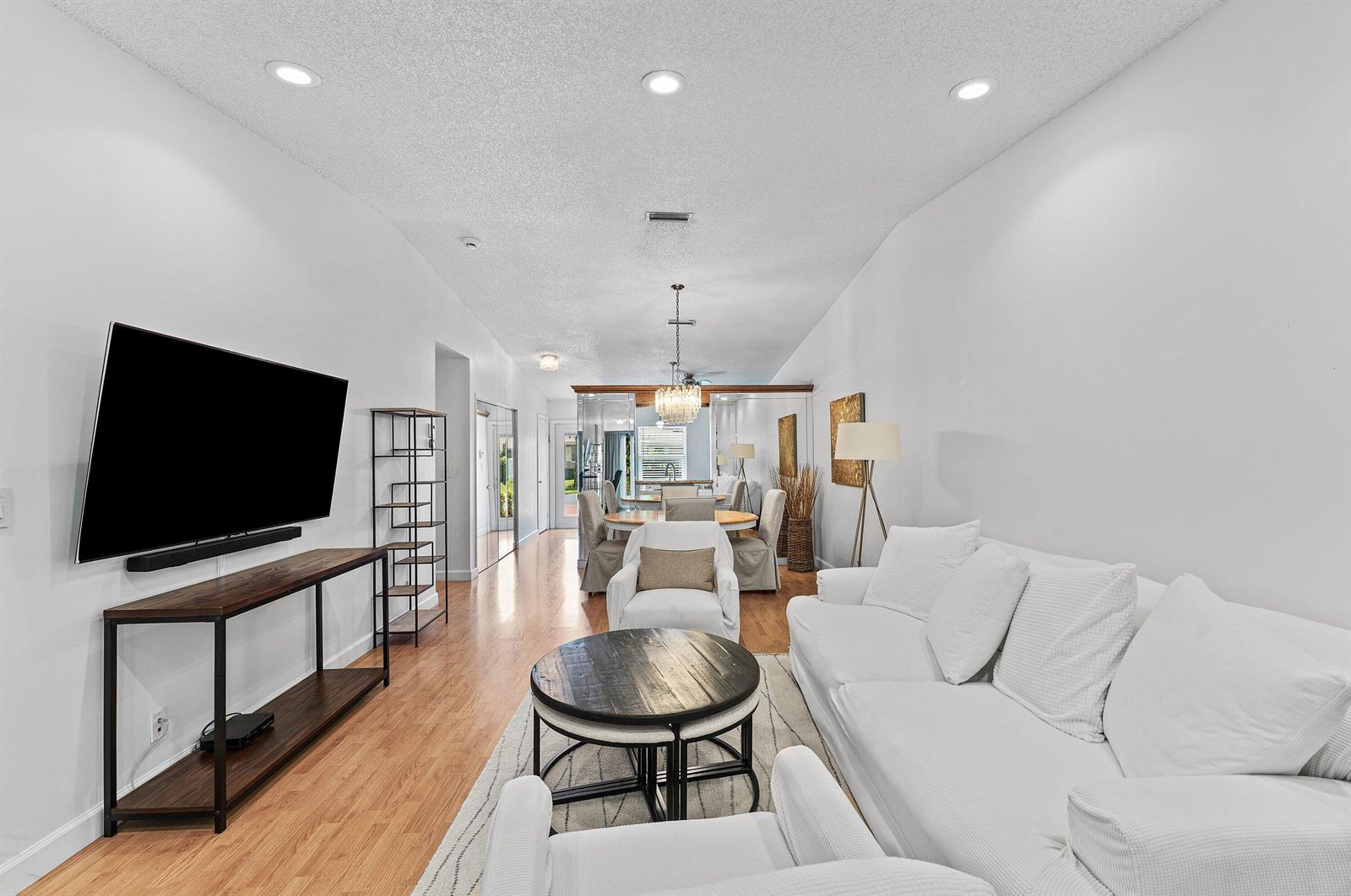 A living room with white furniture, a dark wood coffee table, and hardwood flooring — 18855 Candlewick Drive, Boca Raton FL 33496, BOCA RATON, FL