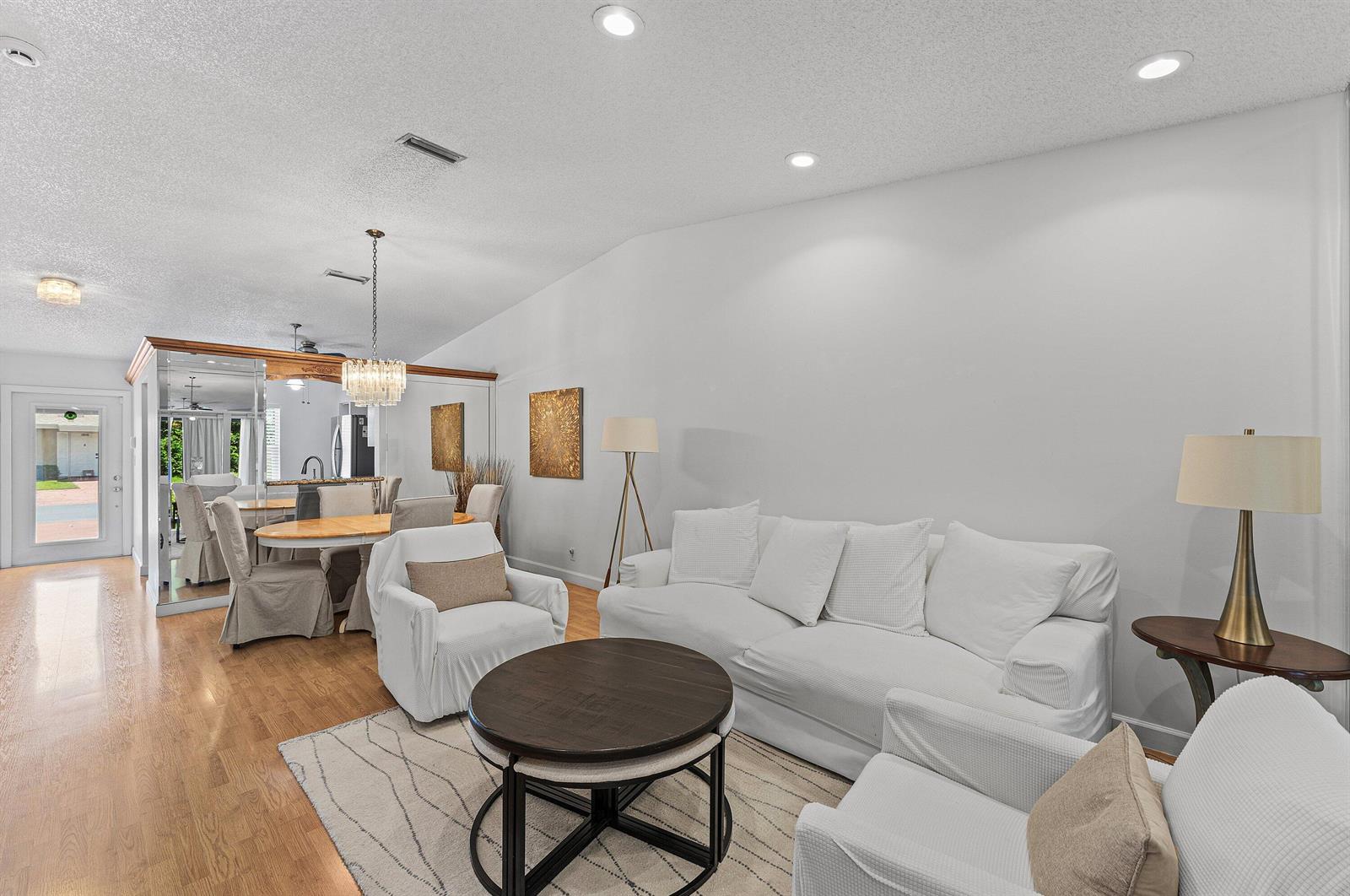 A living room with white furniture, a round coffee table, and an adjacent dining area — 18855 Candlewick Drive, Boca Raton FL 33496, BOCA RATON, FL