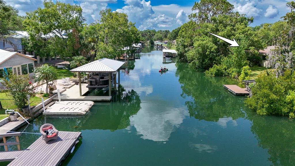 An aerial view shows a canal lined with houses, boat docks, and lush green trees — 1209 SE PARADISE AVENUE, CRYSTAL RIVER, FL