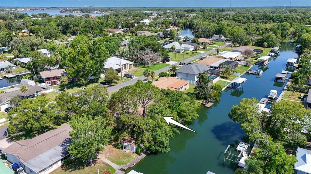 An aerial view shows a waterfront house surrounded by trees with a canal in the foreground — 1209 SE PARADISE AVENUE, CRYSTAL RIVER, FL