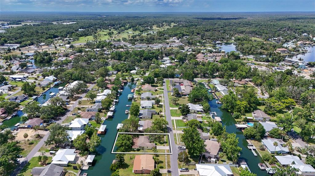 An aerial view shows a single-story house with a white outline on a canal-front lot — 1209 SE PARADISE AVENUE, CRYSTAL RIVER, FL