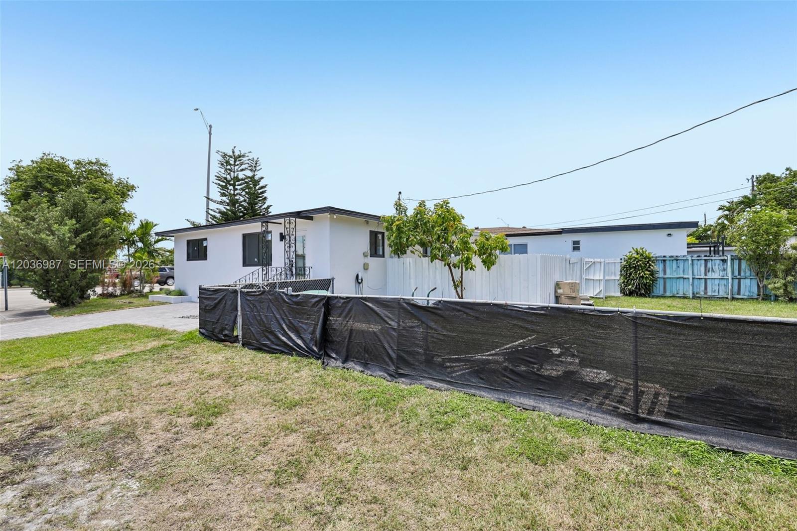A white single-story house features a black privacy screen fence in the front yard — 6595 SW 31st St # 0, Miami FL 33155, MIAMI, FL