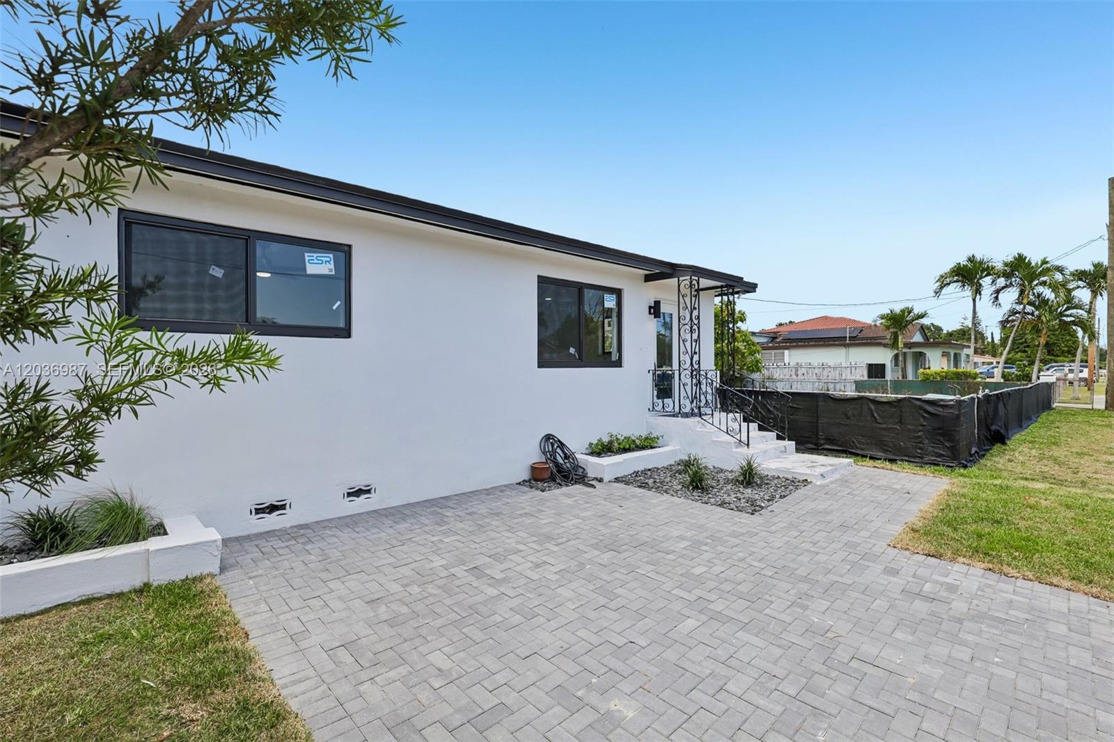 A white house exterior features a paved driveway, black-framed windows, and a small front porch — 6595 SW 31st St # 0, Miami FL 33155, MIAMI, FL